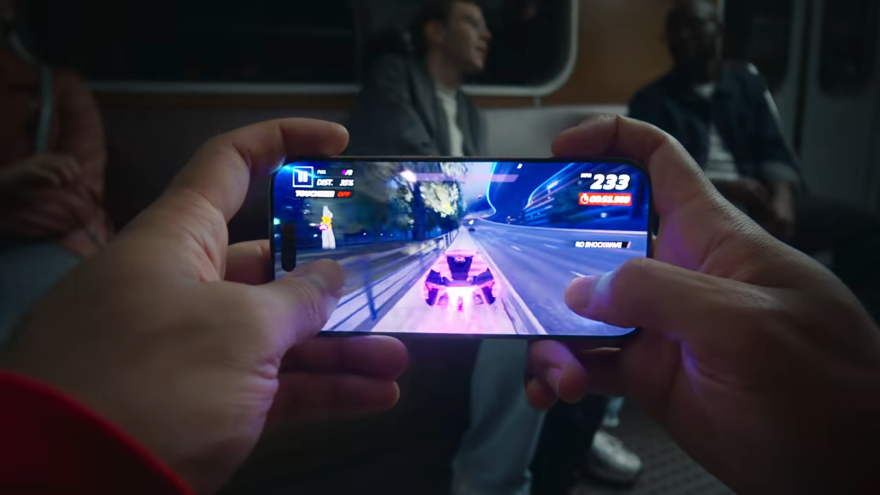 A man&amp;#039;s hands holding the iPhone 16 Pro and playing a video game on it.