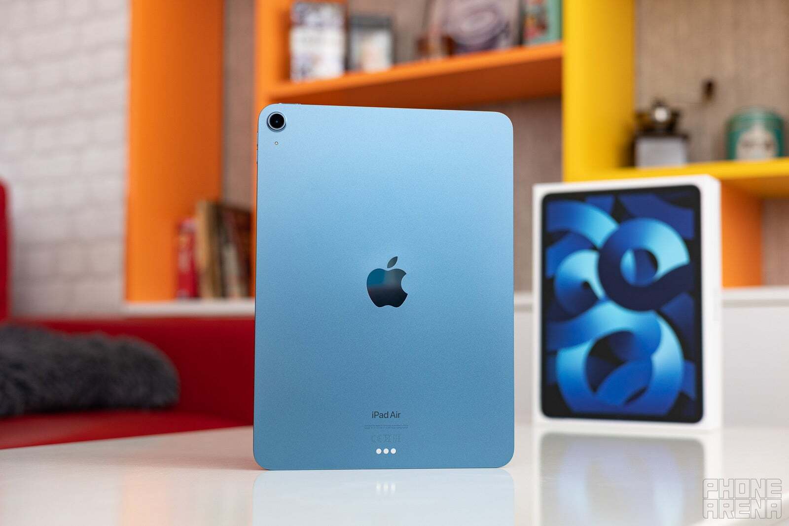 iPad Air (2022) in Blue on a table with its box on the side. 