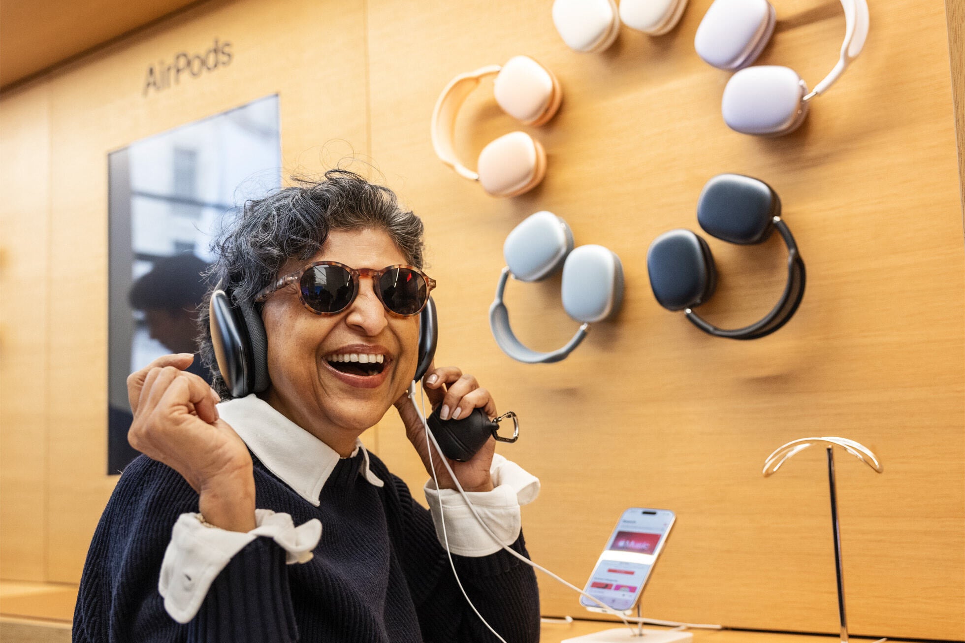 Consumer in London tries on one of the refreshed AirPods Max headphones. | Image credit-Appl - Apple Stores arund the globe were crowded last Friday as the iPhone 16 line was released