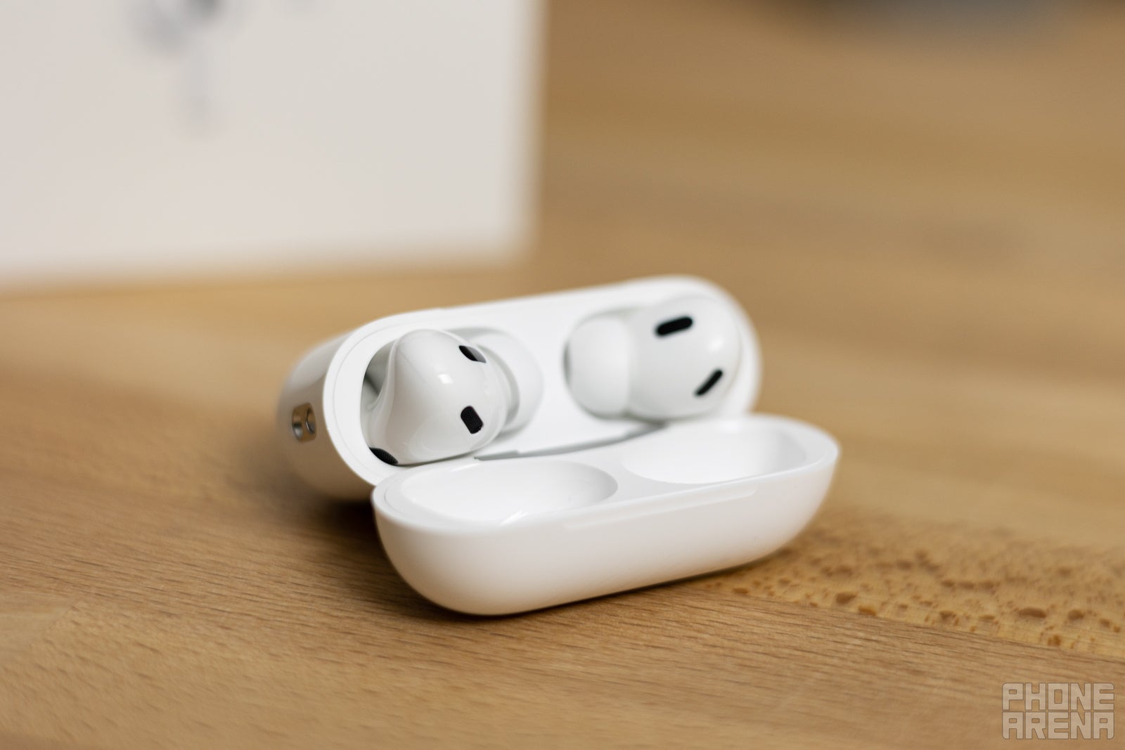 AirPods Pro 2 in their charging case positioned on a wooden table.