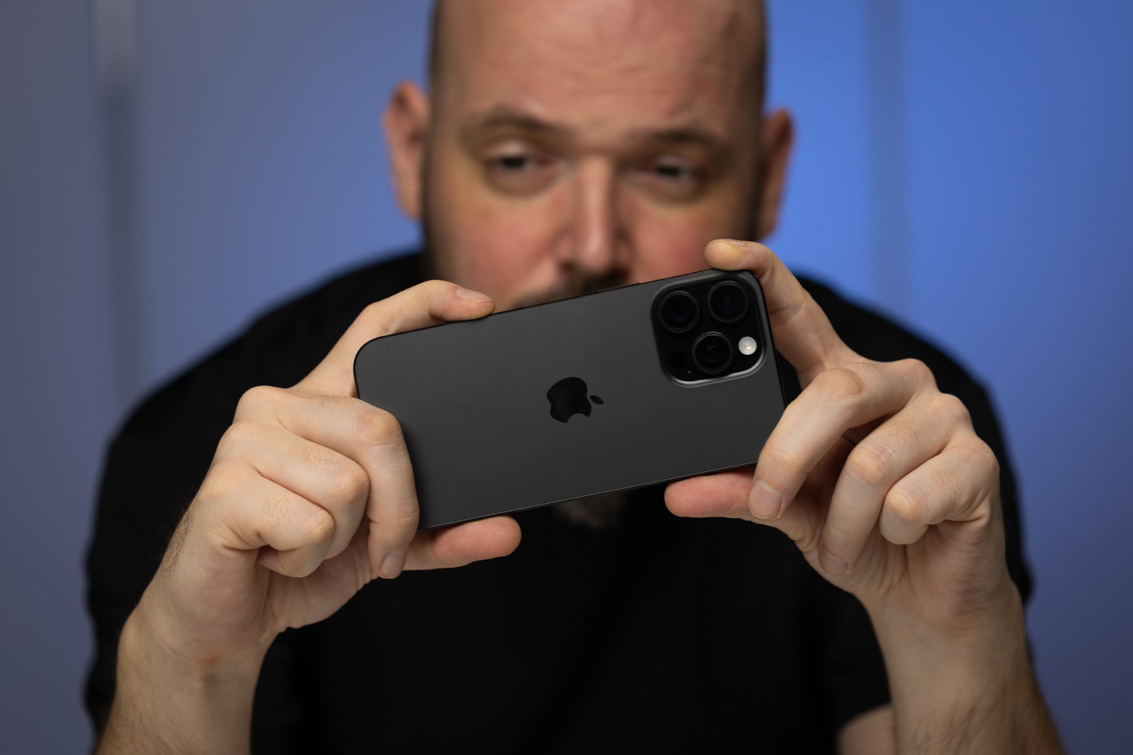 Person holding the iPhone 16 Pro Max horizontally, using the Camera Control button to take photos. The image emphasises how deep into the frame the button is, therefore the grip looks a bit awkward