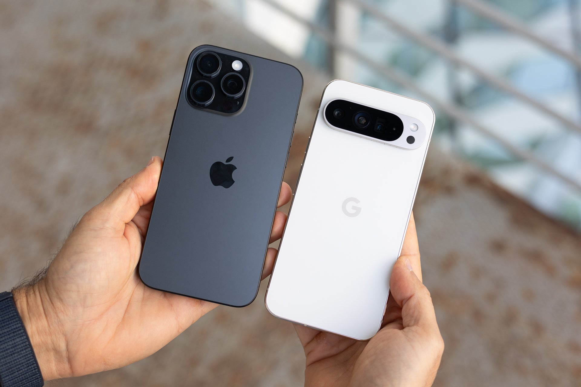 Image of the iPhone 16 Pro Max and the Google Pixel 9 Pro XL being held each in one hand