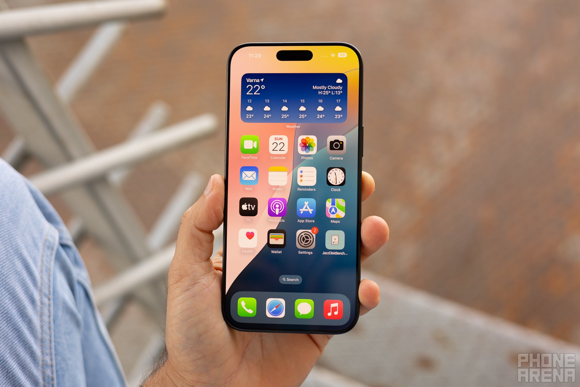 iPhone 16 Pro Max held in hand, screen is on with homescreen visible