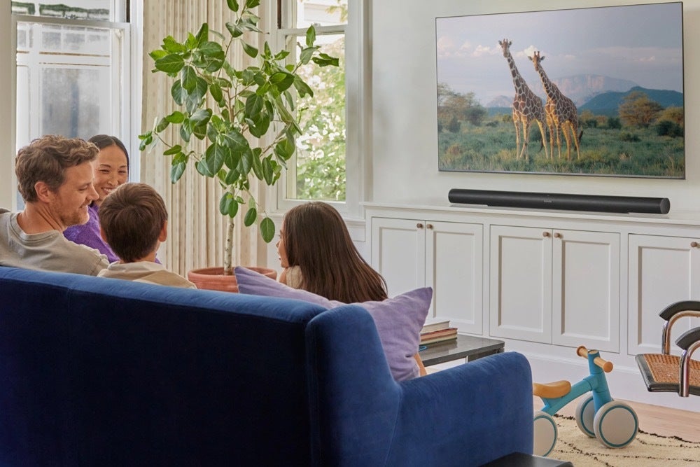 An image of a family sitting on a couch while content plays from a TV with the Sonos Arc Utra soundbar