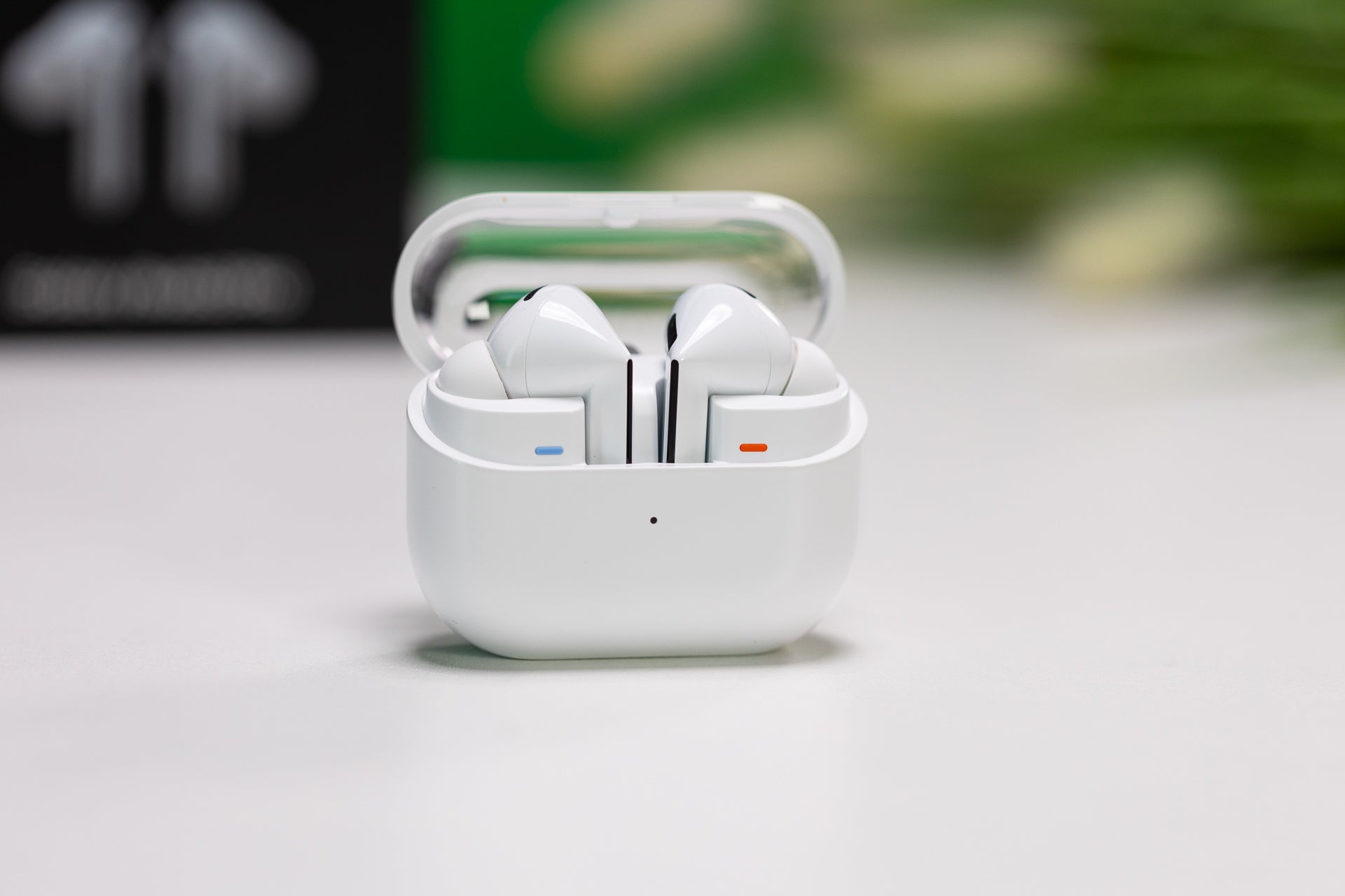 Galaxy Buds 3 Pro, placed on a white table in their opened charging case against a blurred background.