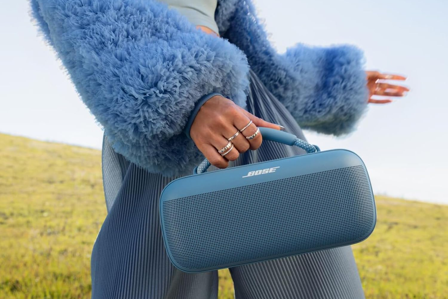 A woman holding the Bose SoundLink Max in Blue in an outdoor setting.