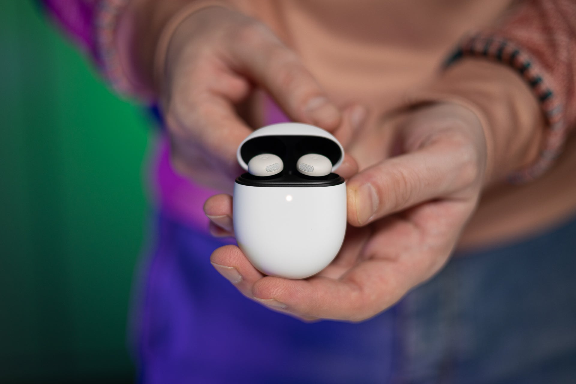 A close-up of a person holding the Google Pixel Buds Pro 2 with both hands.