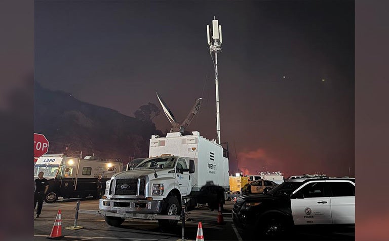 A nighttime scene showing a mobile command center truck with a large antenna deployed.