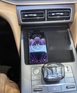 A smartphone is wirelessly charging on a charging pad in the center console of a car.