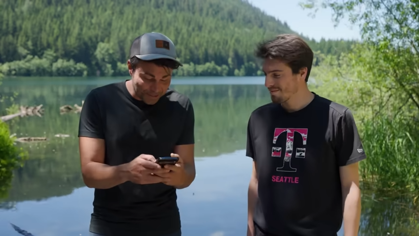 Two men operating a phone in a remote area.