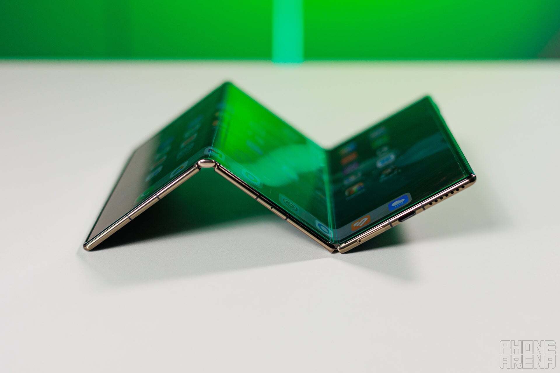 Image of the Huawei Mate XT foldable smartphone in a half-folded position. The device&amp;#039;s flexible display and hinge mechanism are visible.