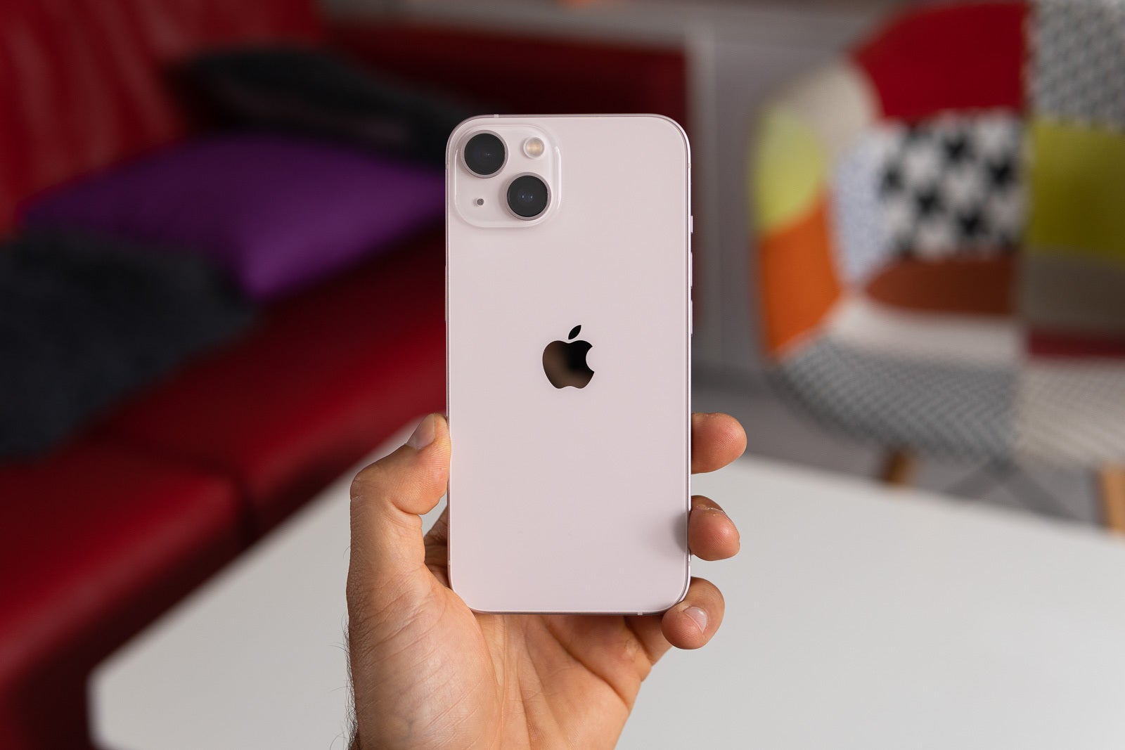 A person holding the iPhone 13 in white in their hand, showing the phone&amp;#039;s back.