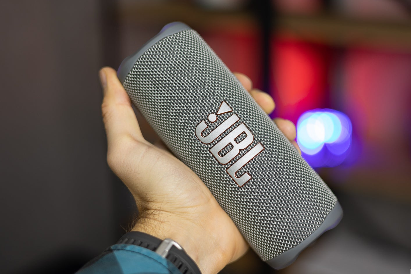 A hand holding the JBL Flip 6, showcasing the speaker&amp;#039;s JBL logo.