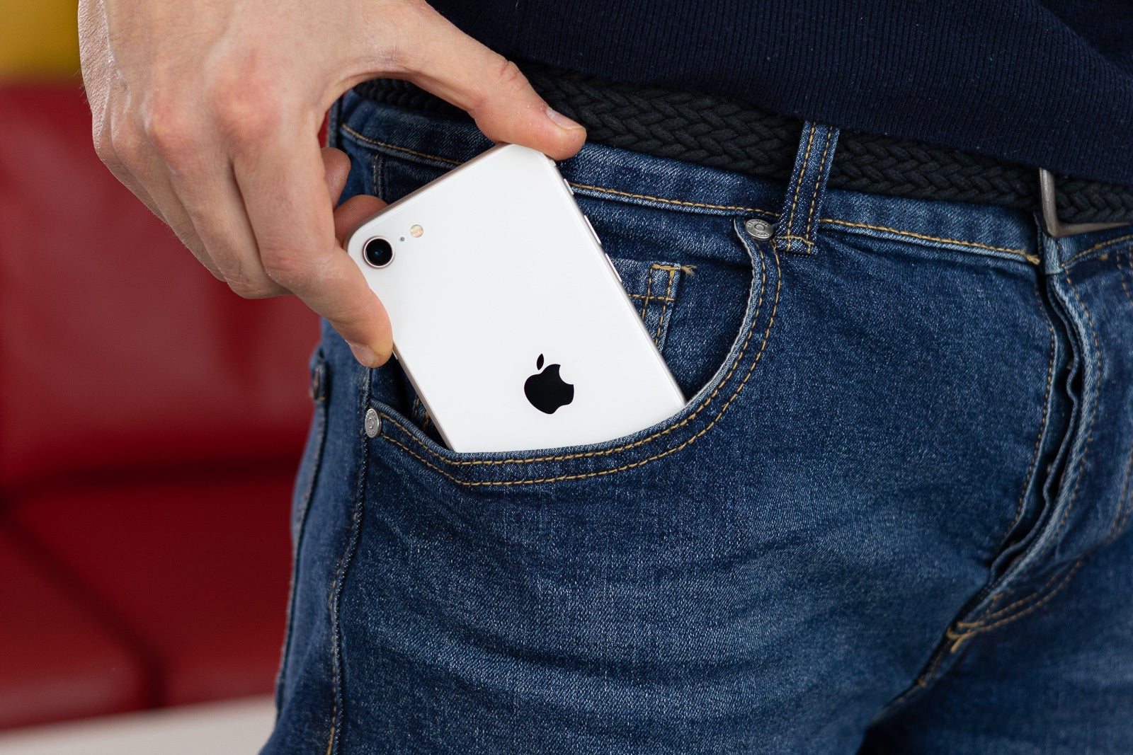 Image of the iPhone SE 3 being slid into a man's bluejeans pocket