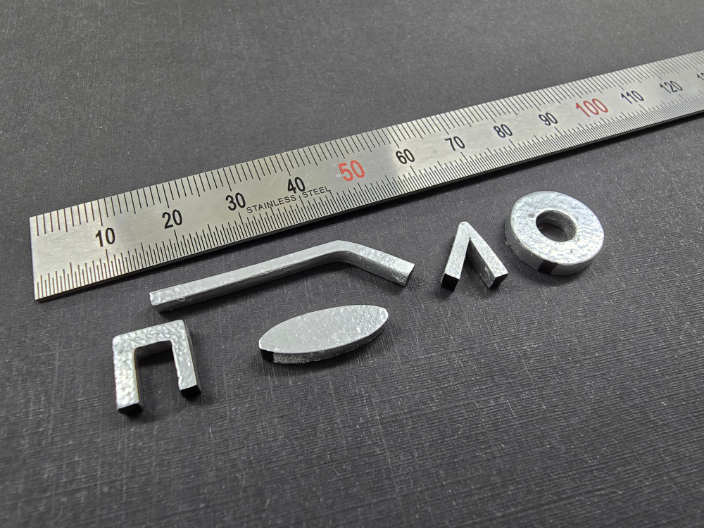 Metal shapes and a ruler on a gray surface.