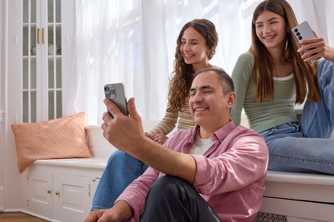 A dad and two girls using smartphones