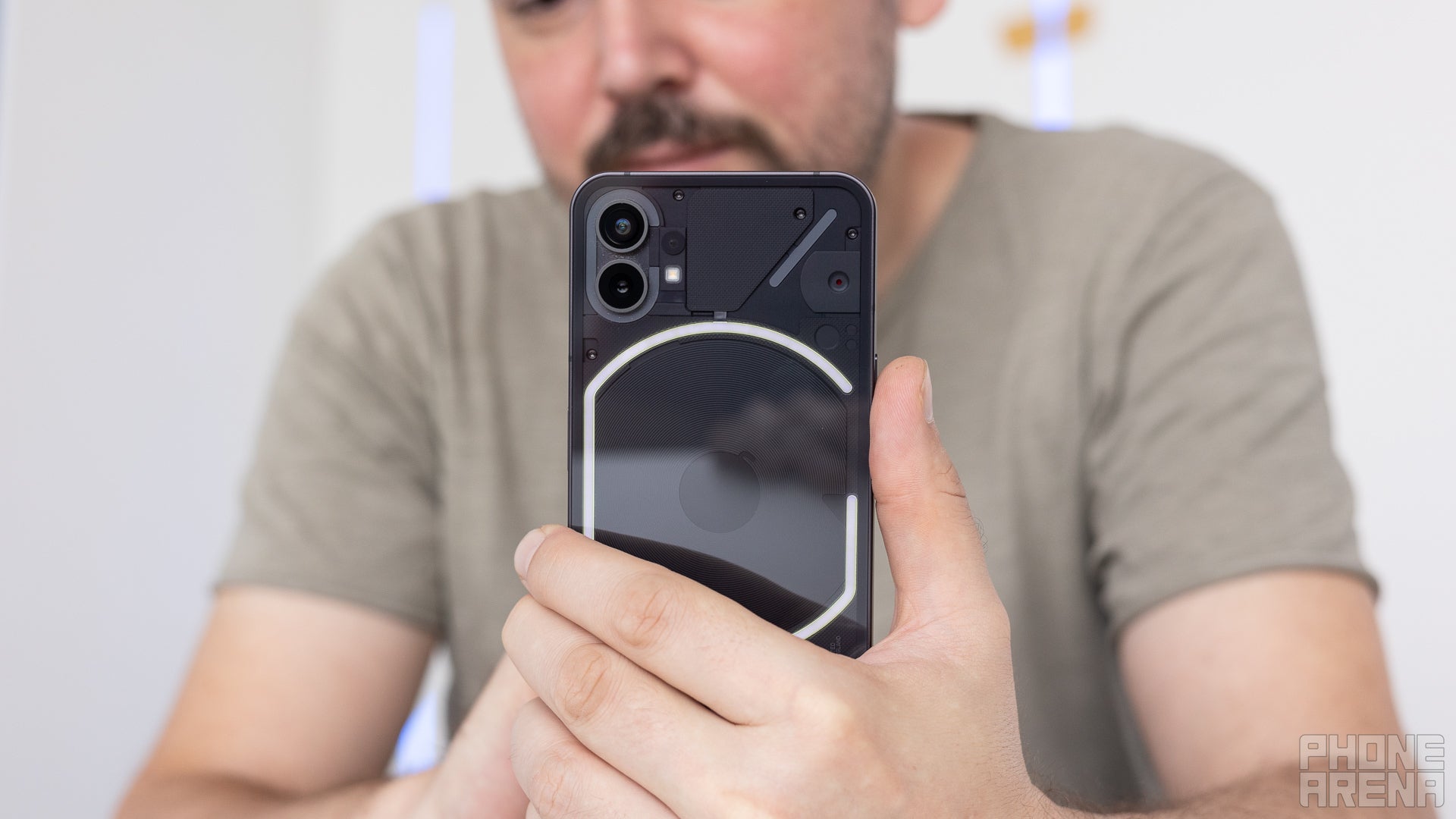 Person holding Nothing (1), phone back towards camera, showing the LED pattern under its glass