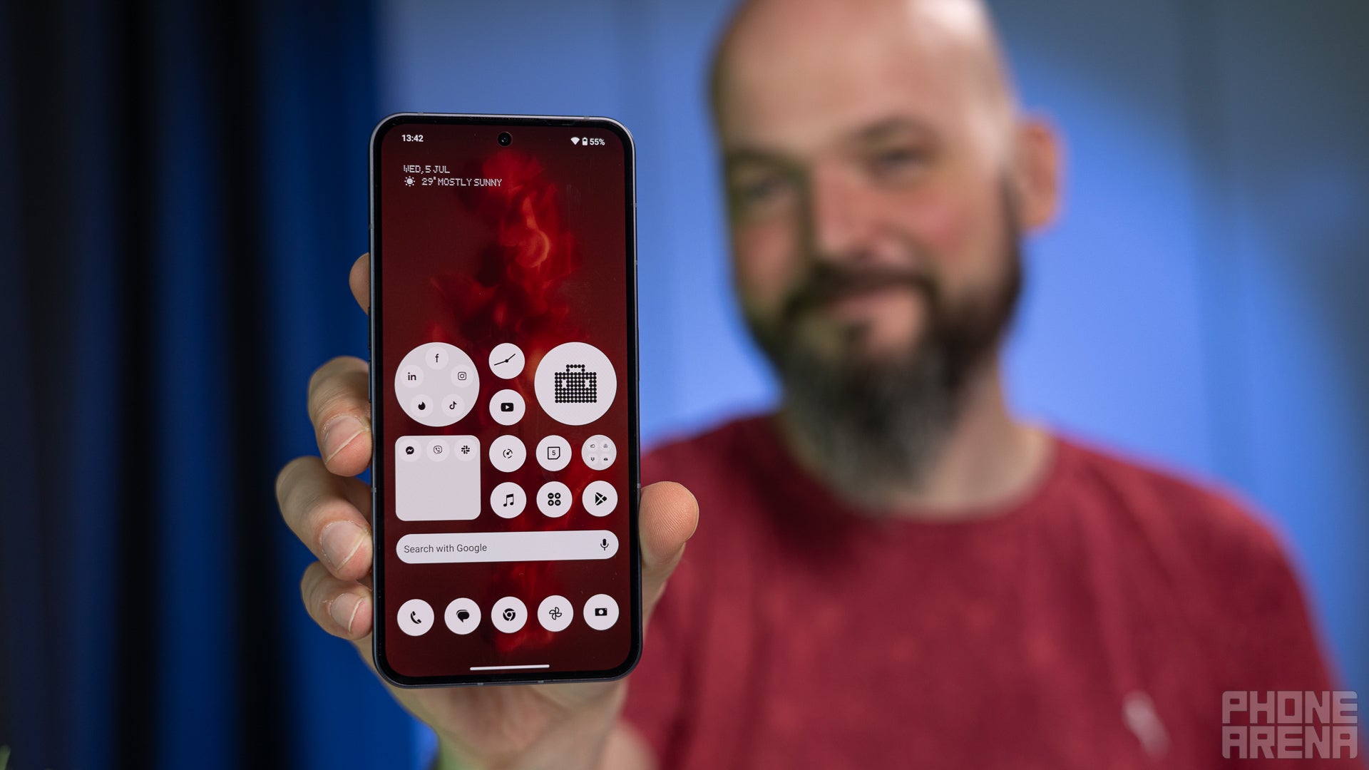 Person holding Nothing Phone (2) with its display towards the camera, showing the homescreen