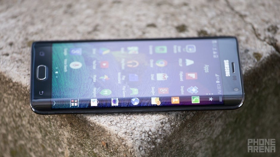 Samsung Galaxy Note Edge em uma formação rochosa em algum lugar ao ar livre. Visto em um ângulo, da lateral da curva de tela. A tela está ligada, mostrando a tela inicial e a barra lateral lançada no aplicativo.