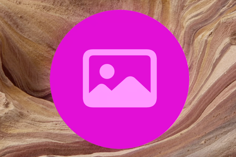 A vibrant magenta circular icon featuring a white outline of a landscape.