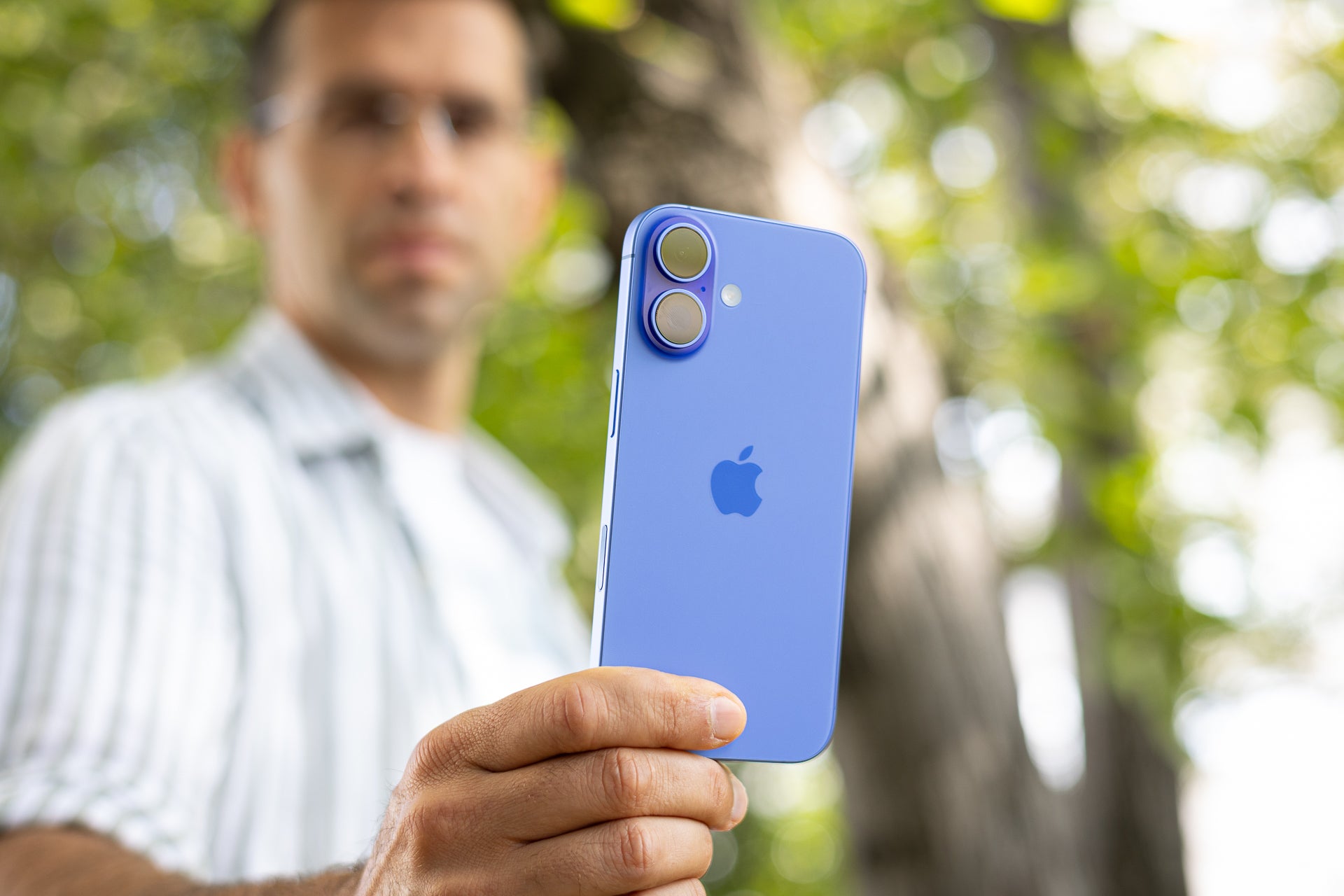 A man holding the iPhone 16 and looking at it.