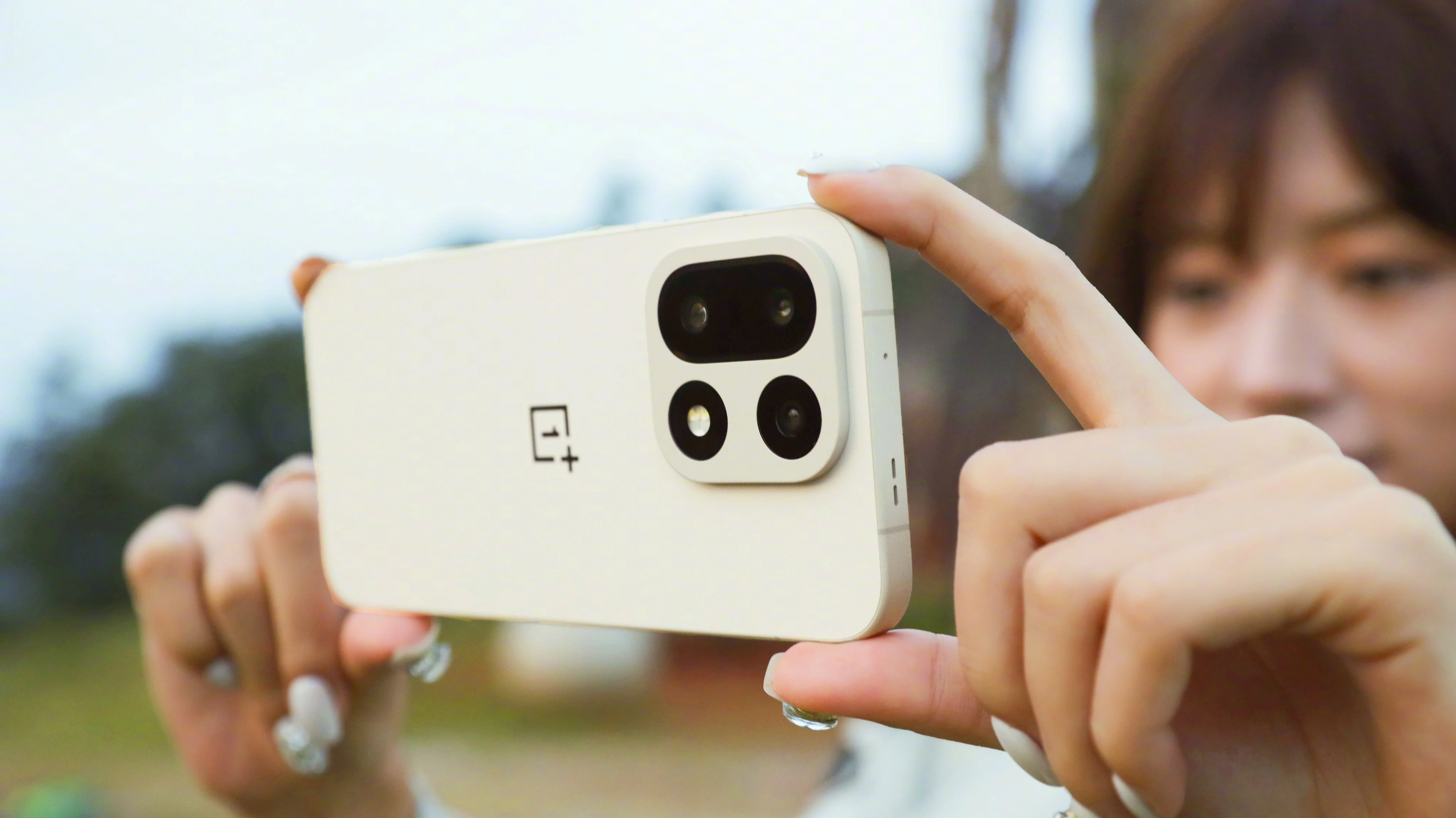 A girl holding the OnePlus 15 in front of her face.