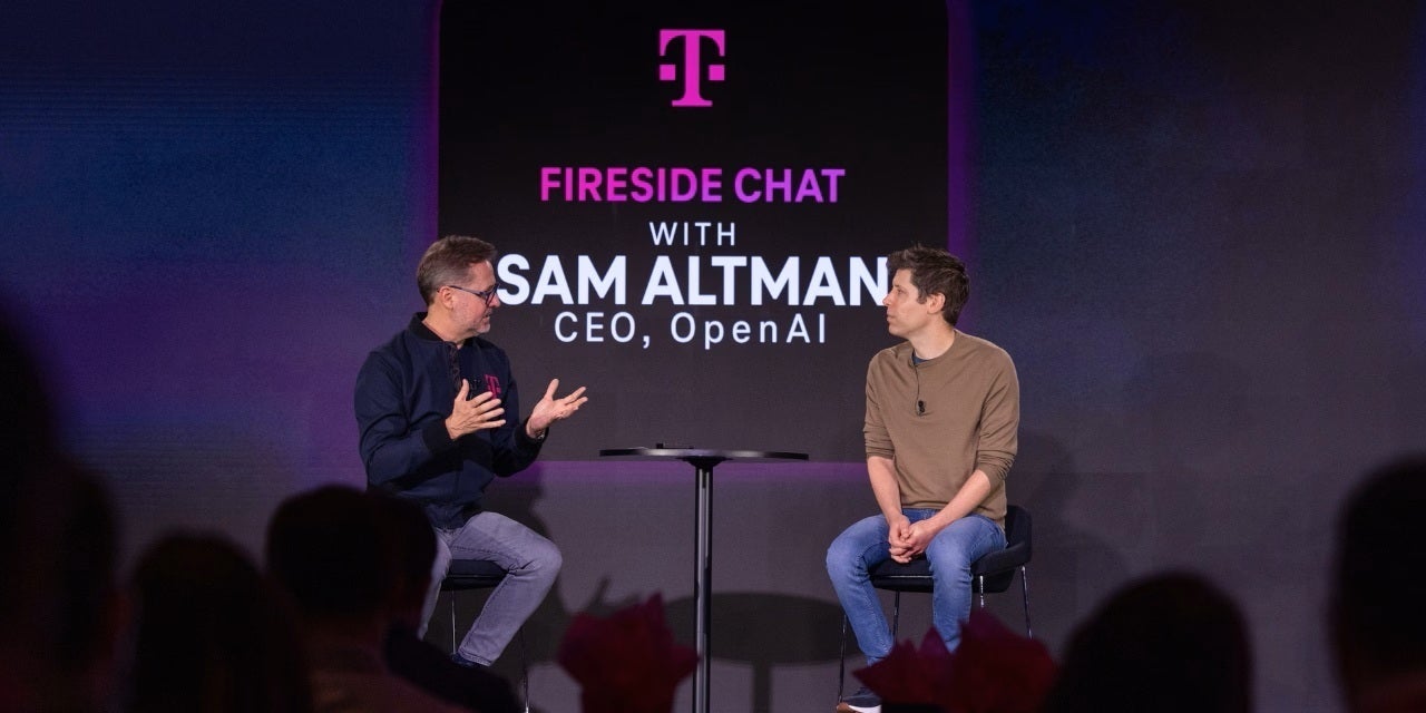 T-Mobile CEO talking to AI wizard Sam Altman on stage.