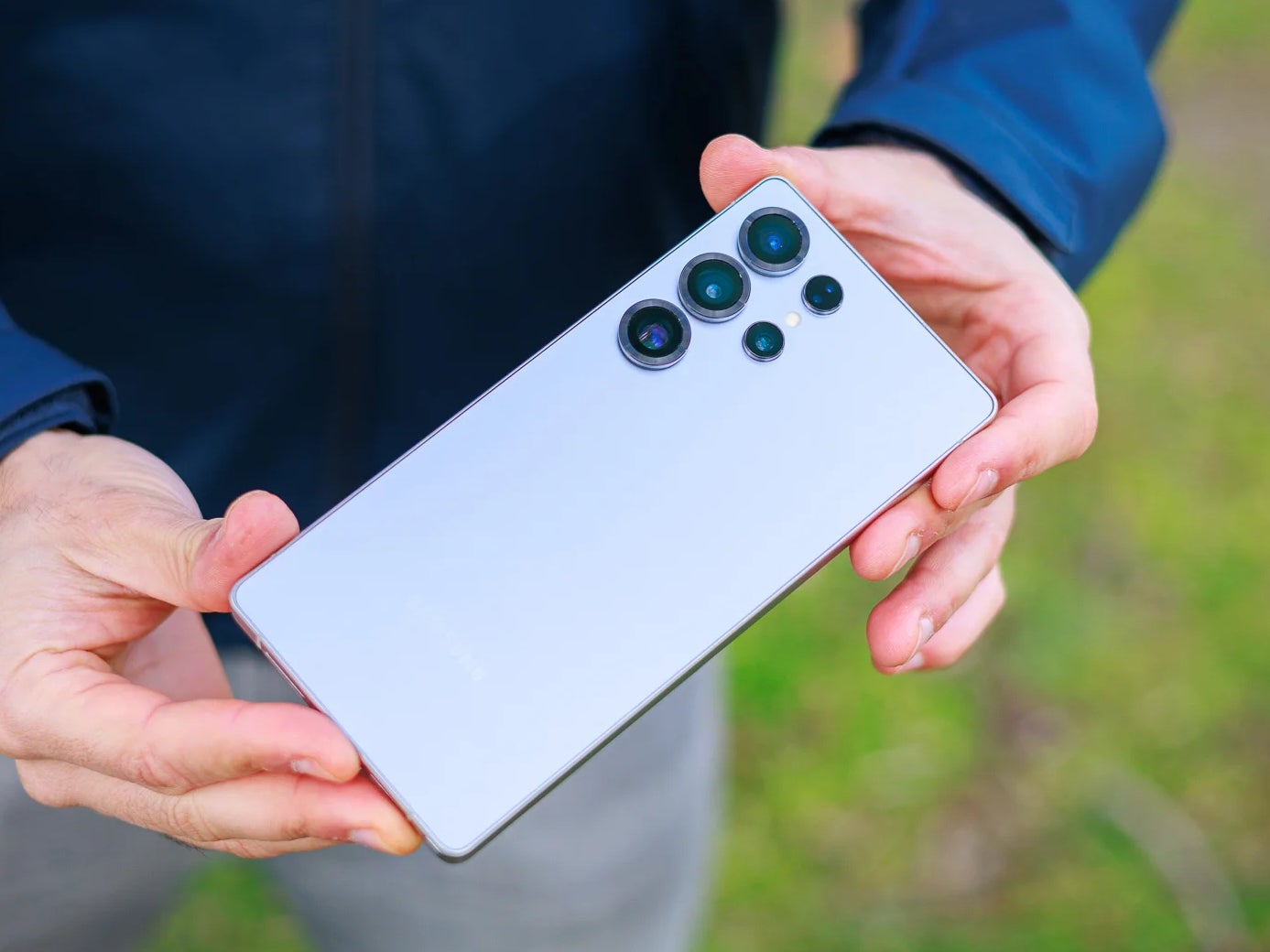 Holding a Galaxy S25 Ultra backside-up outdoors