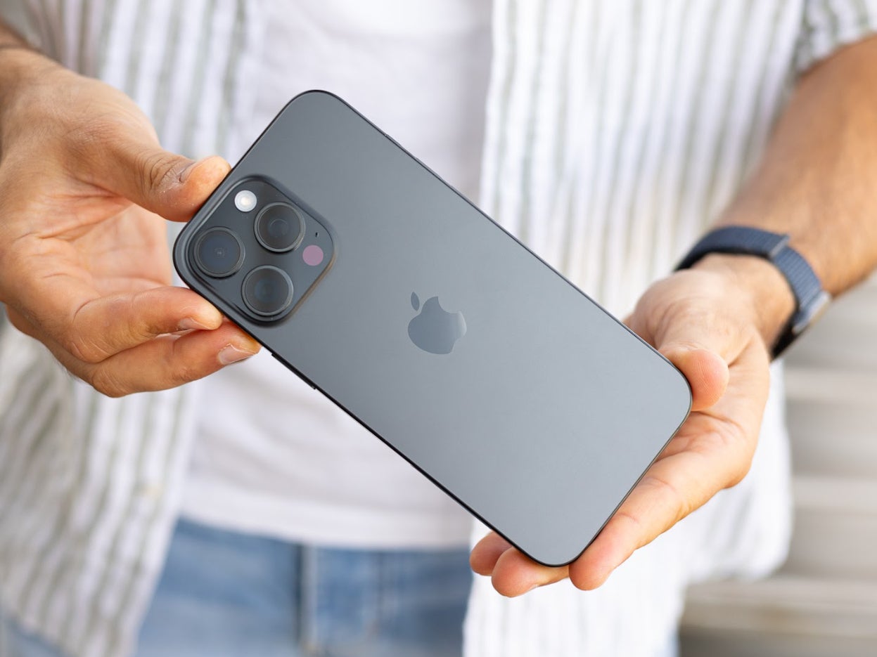 Holding an iPhone 16 Pro Max backside-up outdoors