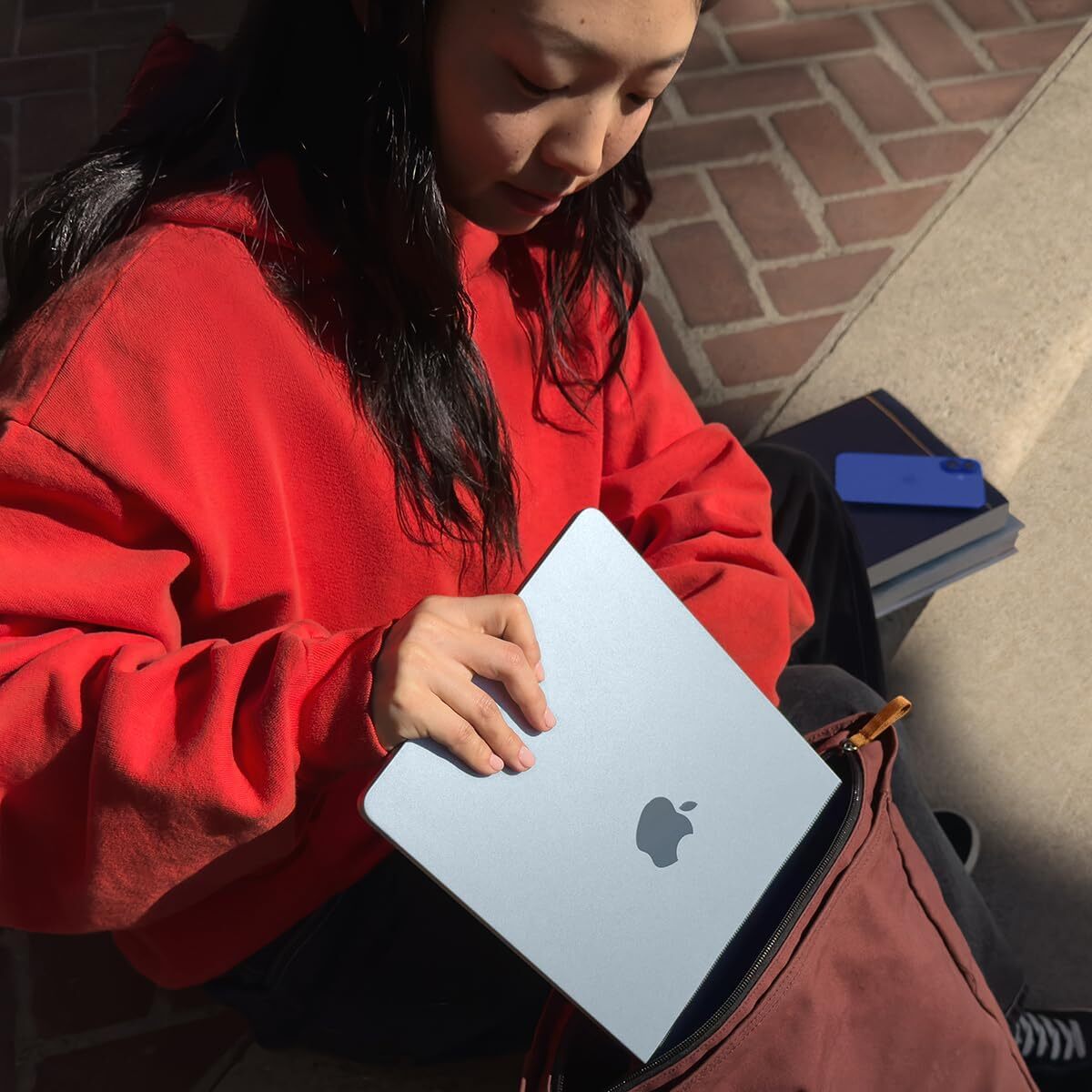 A photo of a girl putting a MacBook Air in her bag.