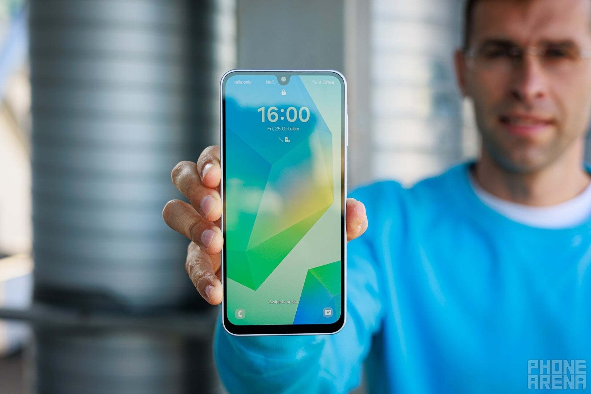 Person holding a phone with a green geometric wallpaper.