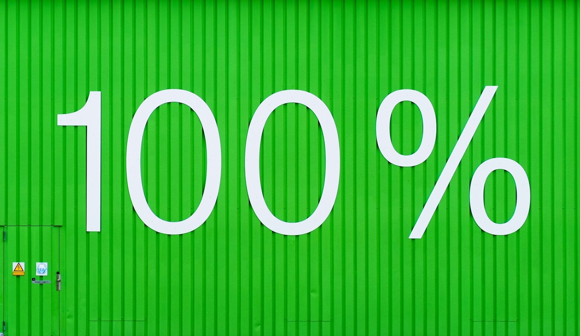 White ‘100%’ text on a bright green corrugated wall.