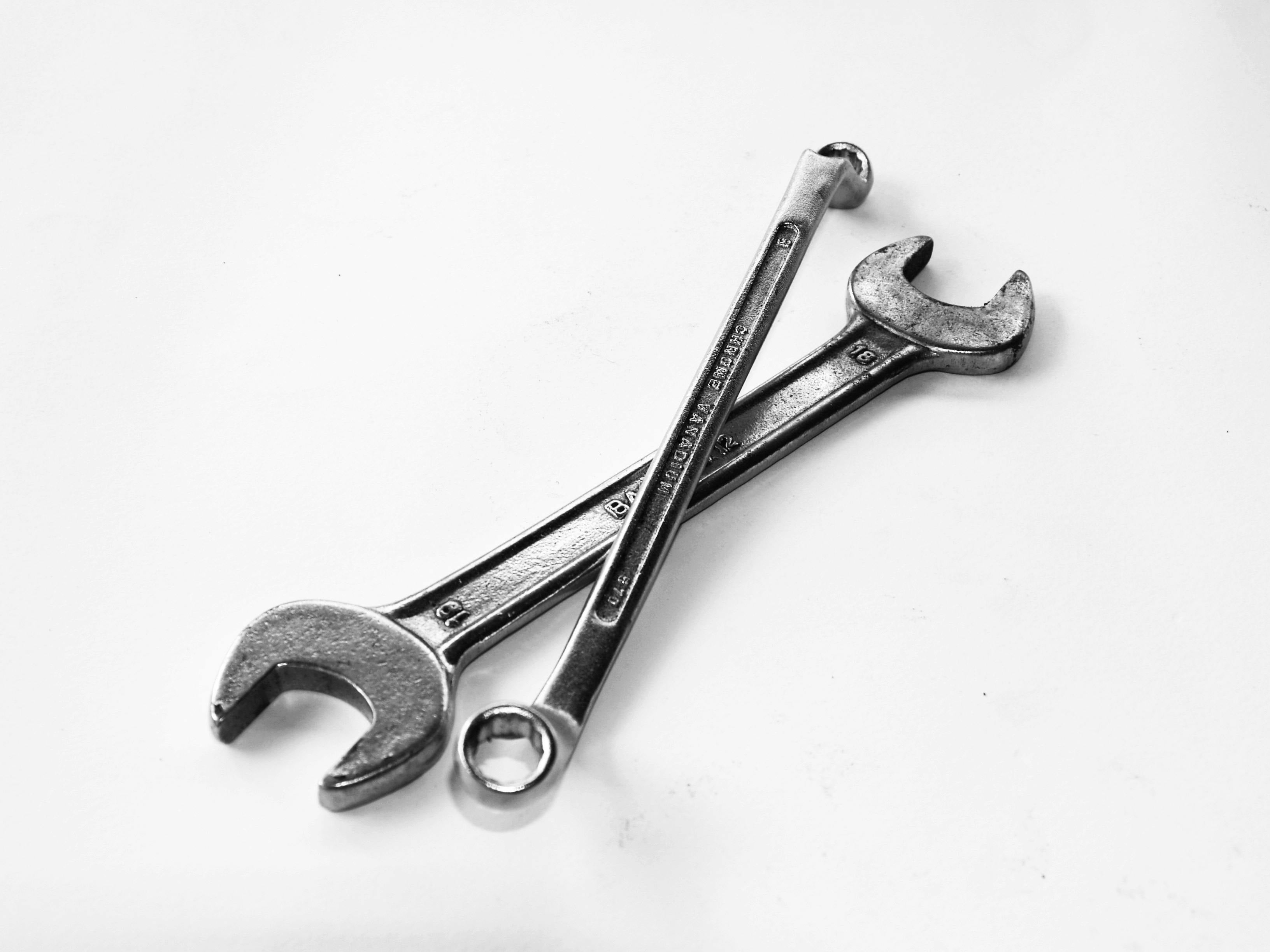 Two silver wrenches crossed on a white surface.
