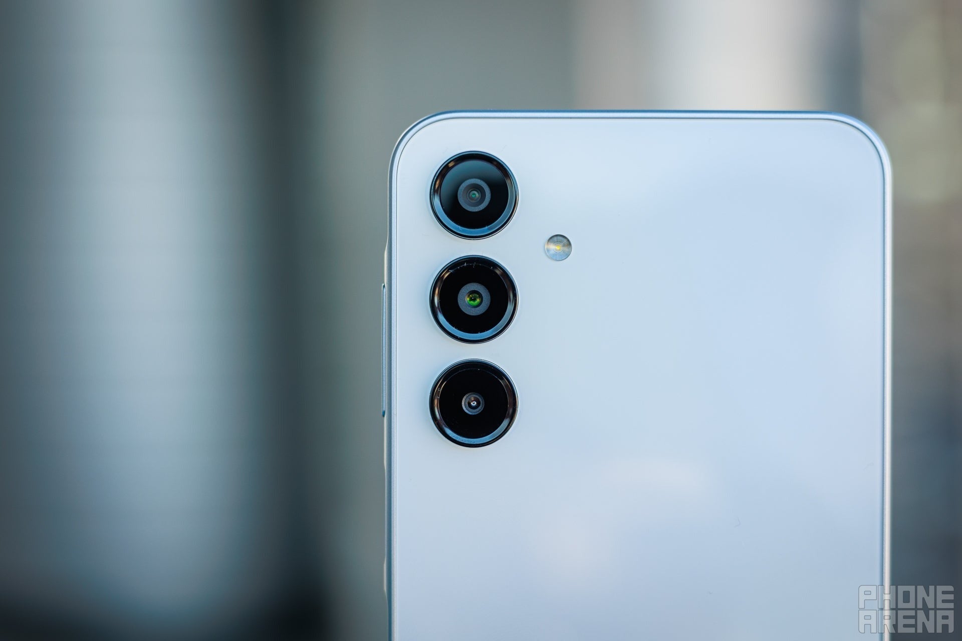 Close-up of a Samsung phone&rsquo;s rear showing three vertically aligned camera lenses and LED flash.
