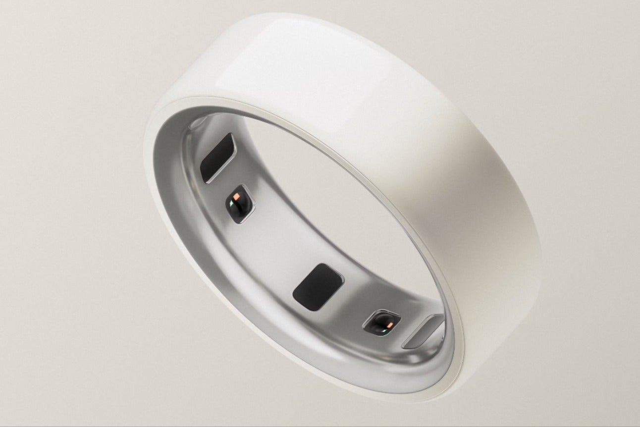 White smart ring with embedded sensors on a light background.
