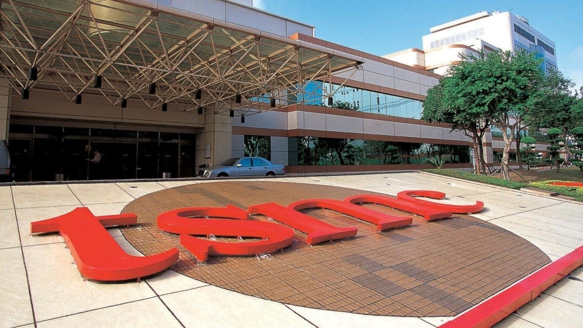 Exterior of a TSMC office building with large red TSMC logo at the entrance.