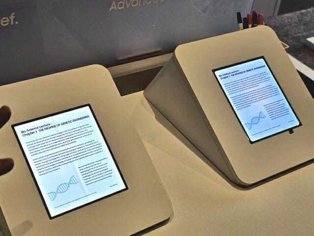 Prototype exhibition stands displaying tablet-style foldable screens with scientific reading content.