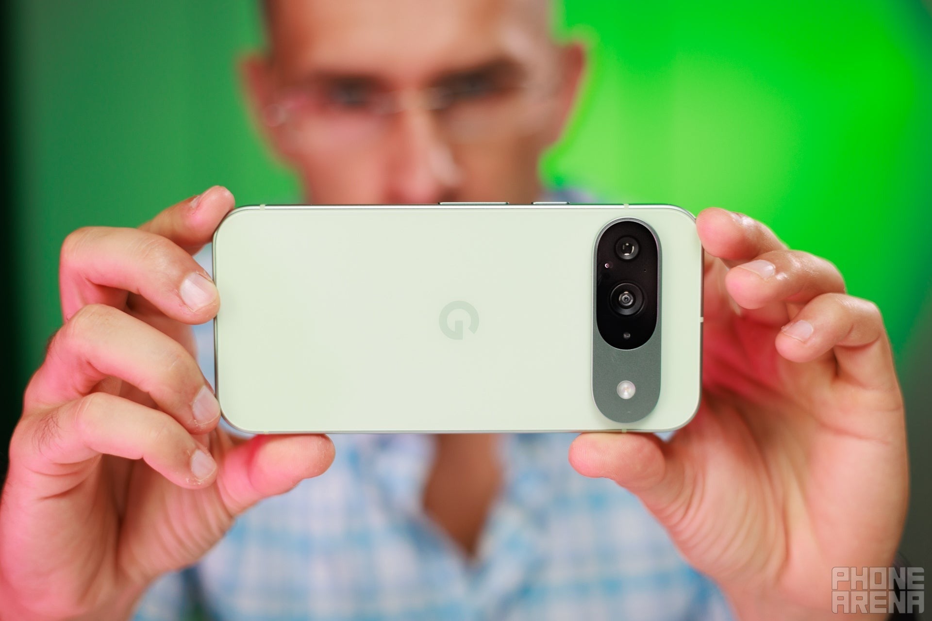 Google Pixel 9 with green back held horizontally as if taking a photo