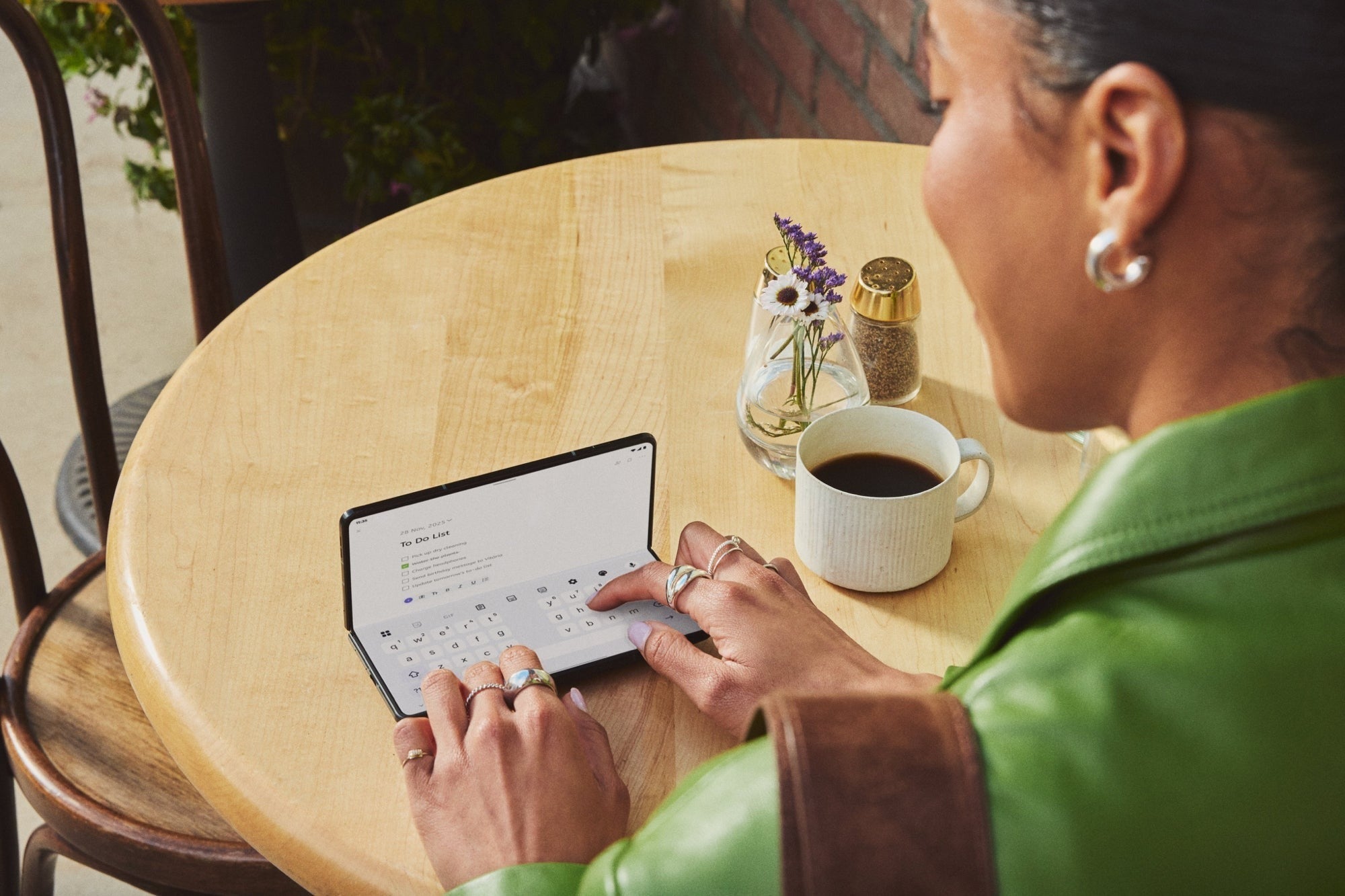 Woman typing on Motorola Razr Fold at a cafe table