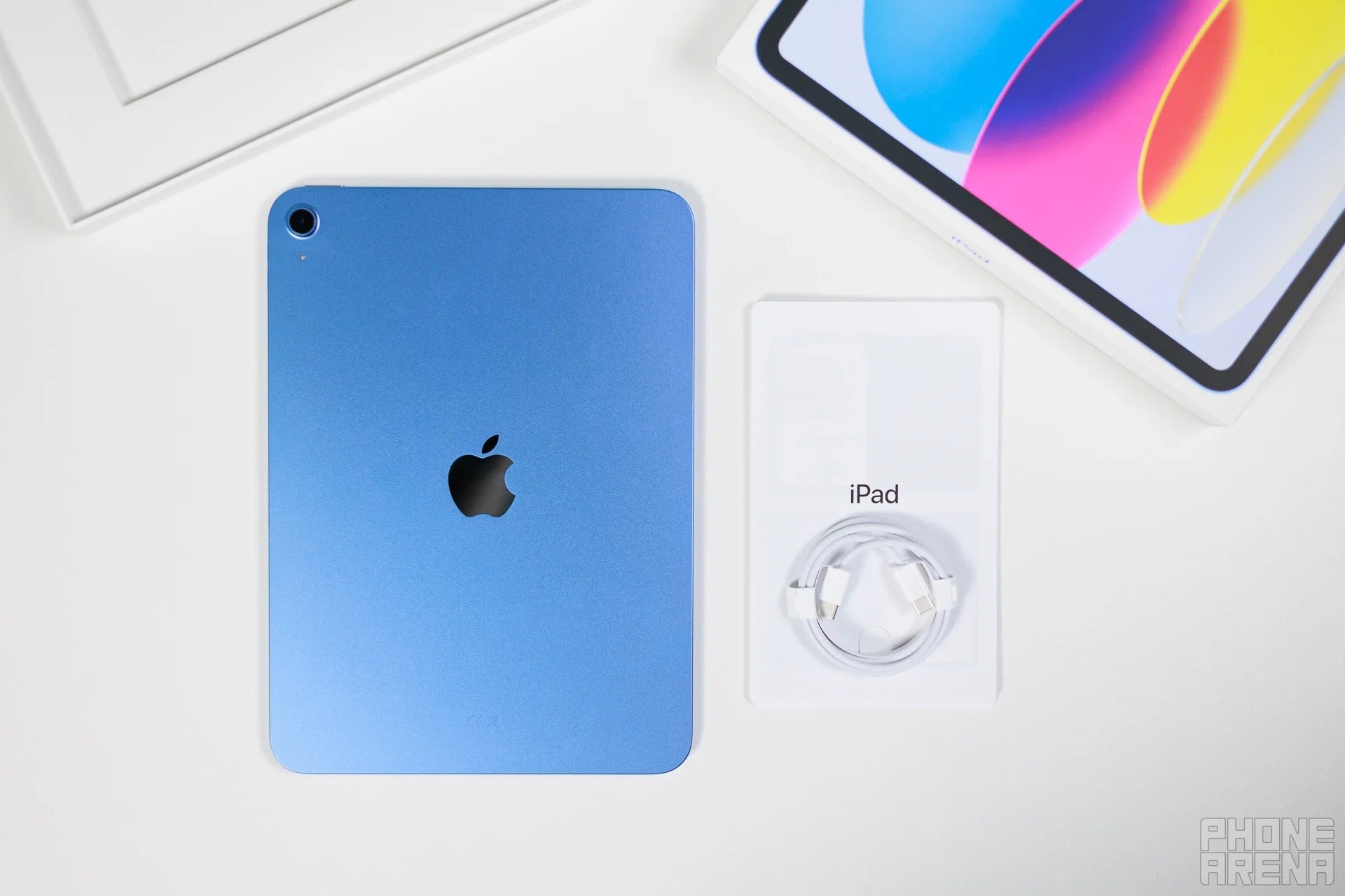 Blue iPad next to box contents including USB-C cable