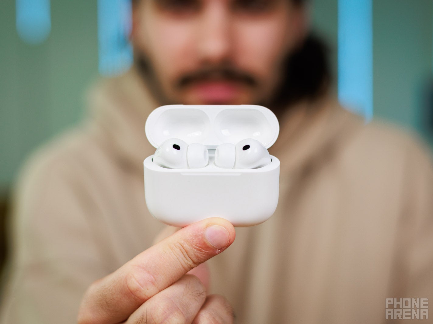 Holding up Apple AirPods Pro 3 in open case