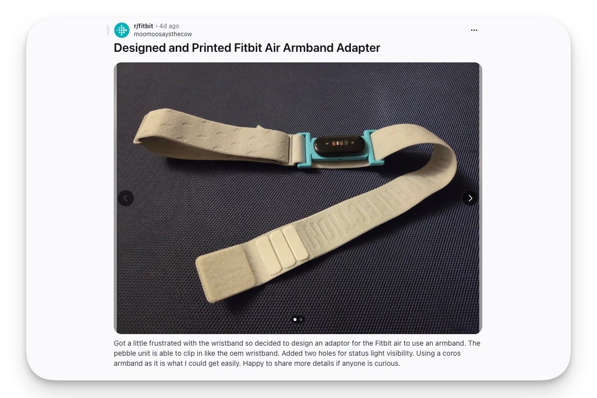 A 3D-printed teal adapter holds a Fitbit Air pebble, attached to a beige fabric armband on a dark surface.