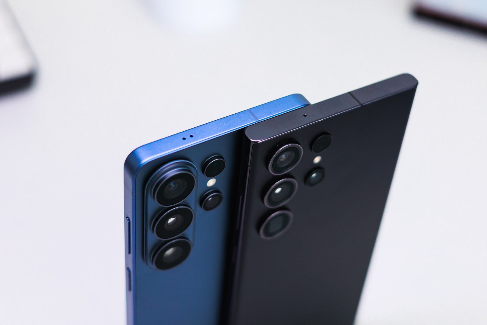 A blue and a black Galaxy S Ultra phones on a desk from the top.