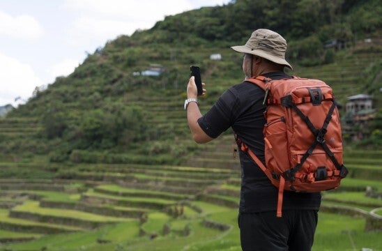Image shows man using cellphone in area without cell service or Wi-Fi.