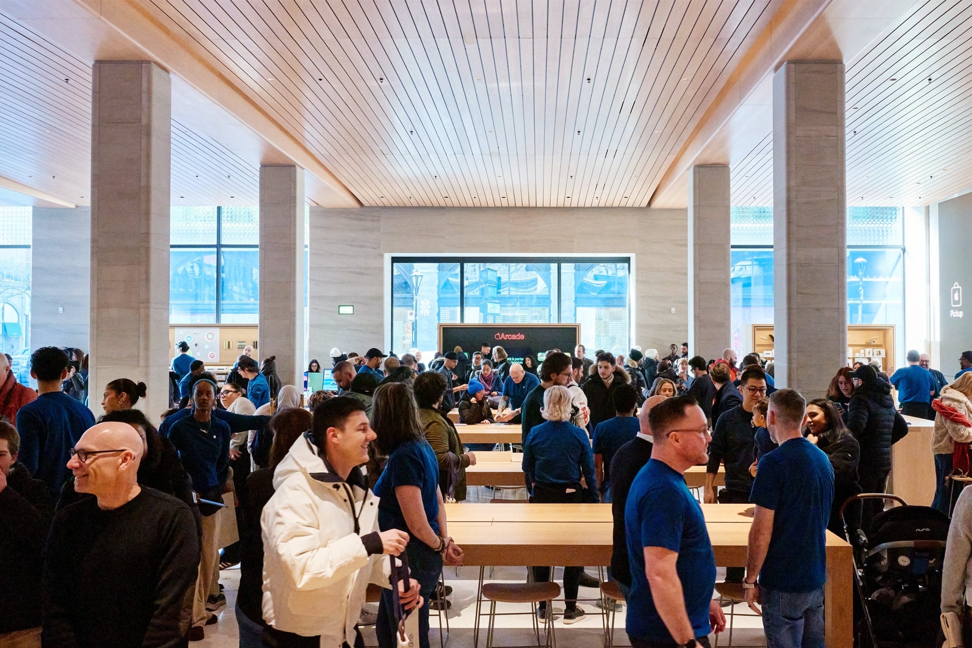 Customers and staff on a busy Apple Store floor with product tables