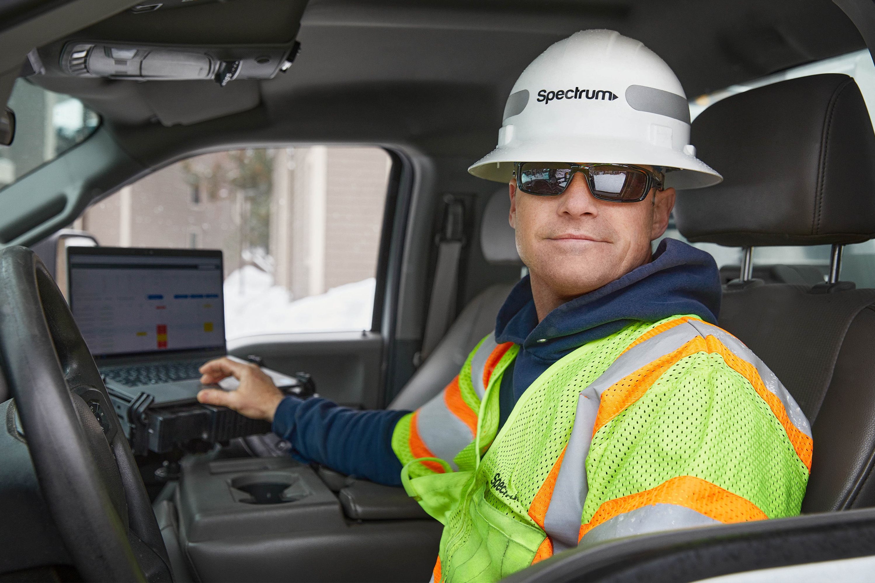 Spectrum field technician working from a laptop in a service truck