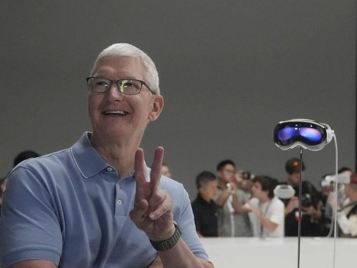 Ex-Apple CEO Tim Cook posing next to an Apple Vision Pro headset
