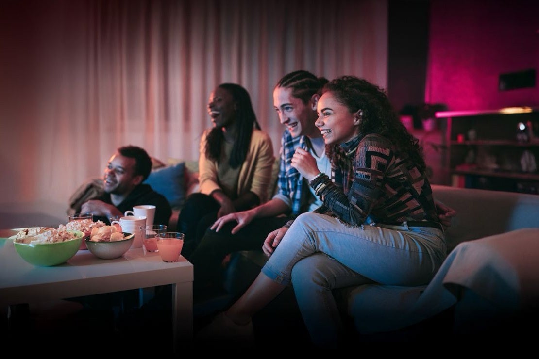Four friends watching TV together on a couch at night