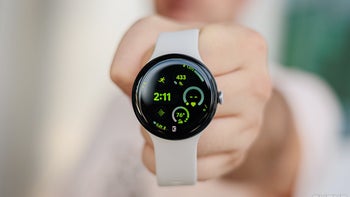 A person's hand holding a Pixel Watch 3 smartwatch with a white band.