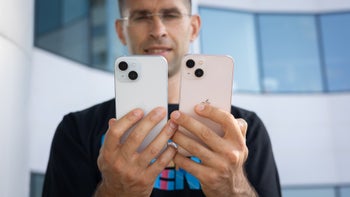 Person holding iPhone 15 next to iPhone 13